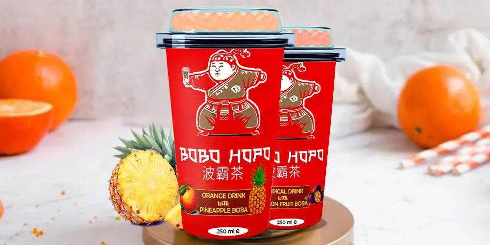 BOBO HOPO bubble teas in bold red 250ml cups, showcasing Orange with Pineapple Boba and Tropical with Passion Fruit Boba, surrounded by fresh pineapple and citrus fruits.